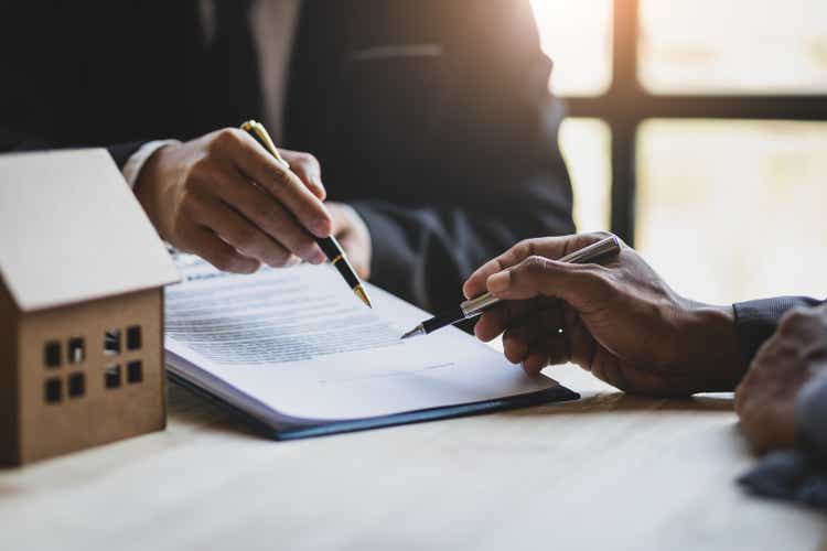 Businessmen and real estate agents discussing documents signing a legal purchase of a house.