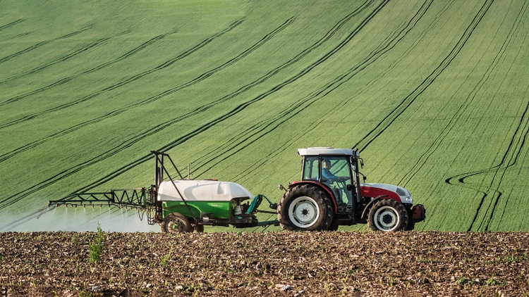 Tractor spraying the crops with pesticides in agricultural field
