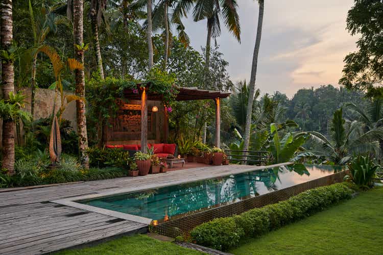 Sitting area next to pool at luxury villa situated amongst tropical plants and valley view