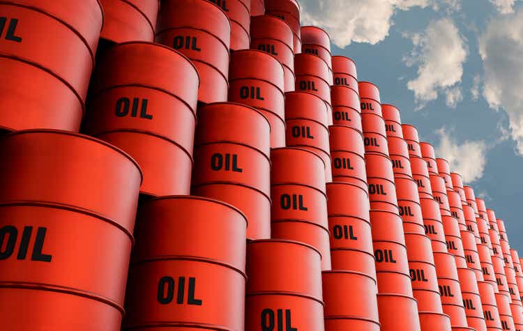 Staked red oil barrels against cloudy sky.