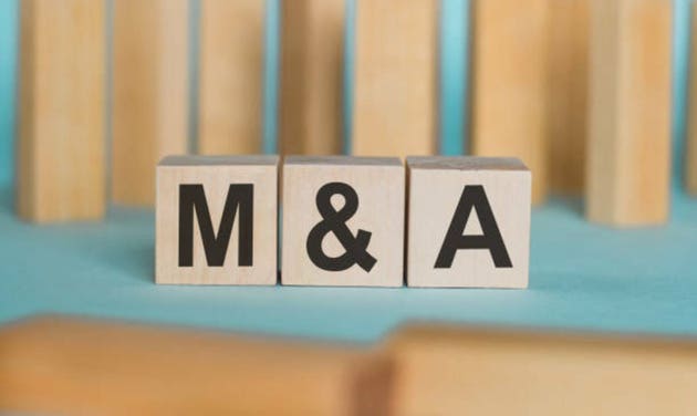 Wooden blocks with text M and A on light blue paper, business concept. MA - short for mergers and acquisitions
