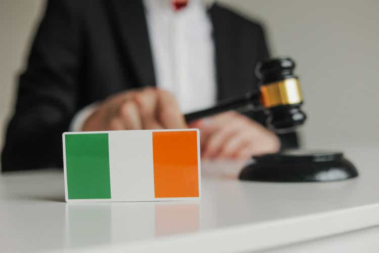 Judge"s hand holding wooden gavel. Flag of Ireland. Concept of Irish justice system