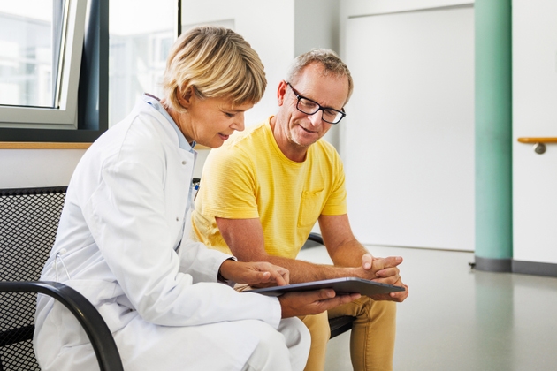 Female Doctor and Senior Patient Discussing Health Plan Using Digital Tablet