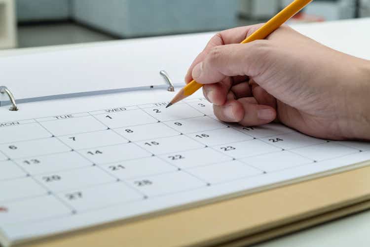 Woman hand with pencil writing on calendar page