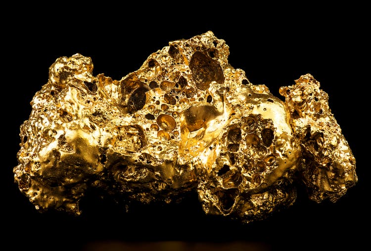 Pure gold from the mine on black background. Closeup of gold nugget. Finance and business concept.