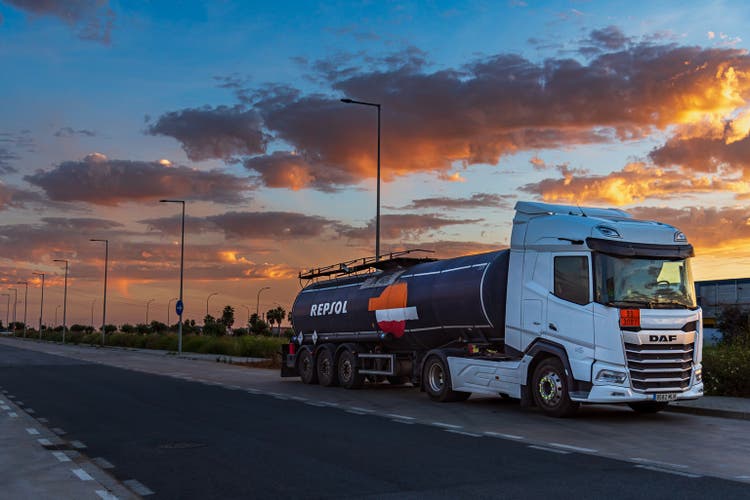 Camión cisterna con el emblema de la compañía energética Repsol pintado en el camión cisterna, con un cielo dramático al atardecer.