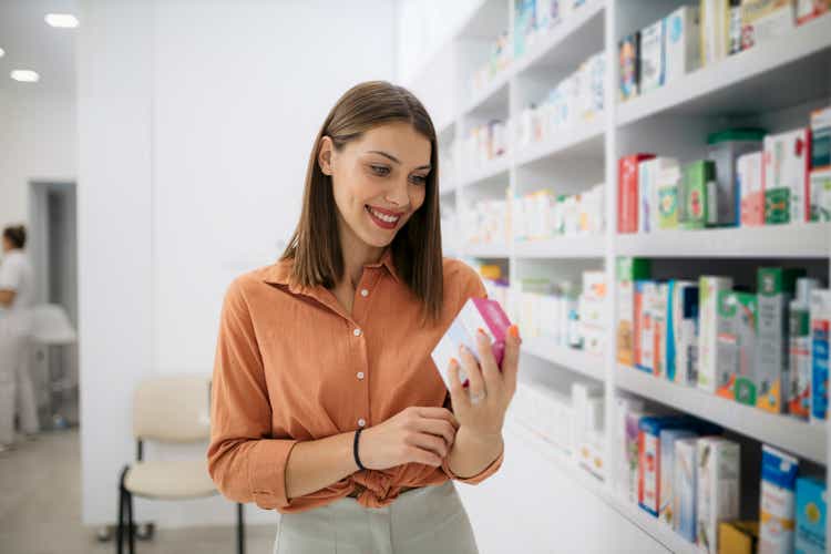 Smiling woman checking contents of medicine at pharmacy