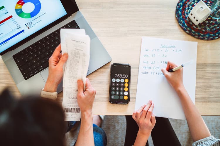A direct above and personal perspective shot of mother and daughter managing home budget at home with the aid of A.I. financial app at home.