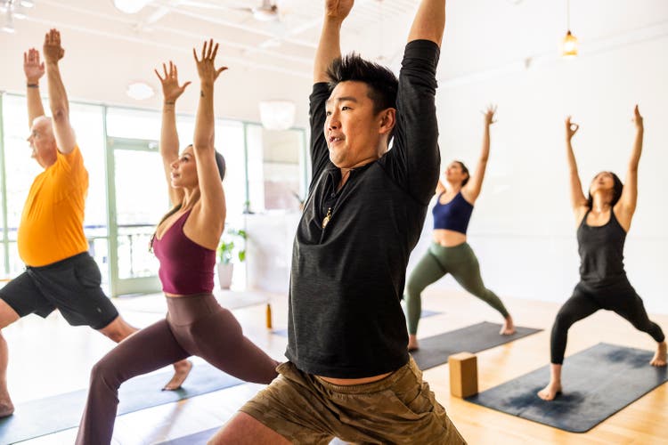 Diverse group of students doing crescent lunge pose during yoga class