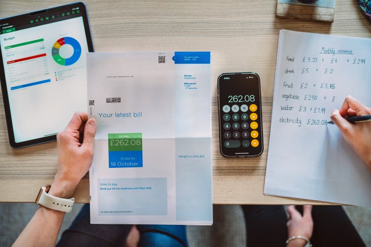 Directly above shot of mother and teenage daughter learning finance together at home with a focus on water usage with the aid of AI financial app.