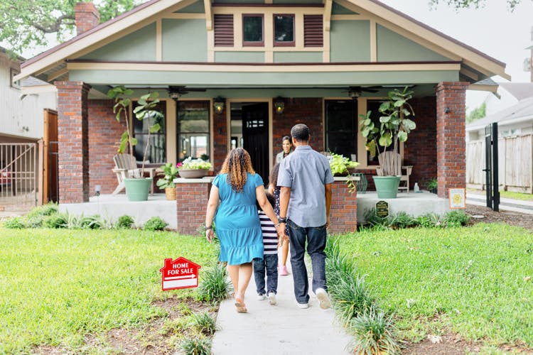 A family meeting with a real estate agent in front of the house on sale