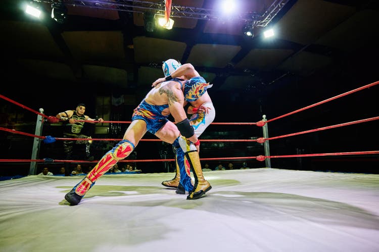 Wide shot luchador trying to take down opponent during lucha libre match