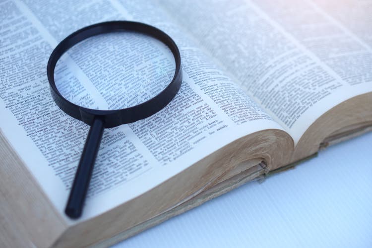 Megnifying glass on page of dictionary. Concept, Word searching. Education
