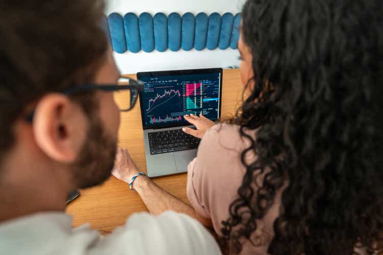 Hispanic Couple Analyzing Financial Charts on Laptop