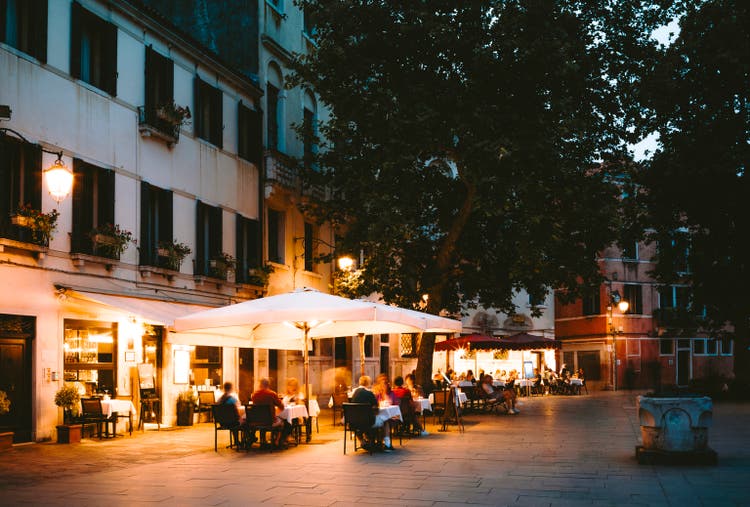 People dining outside street cafes and restaurants at night in Venice