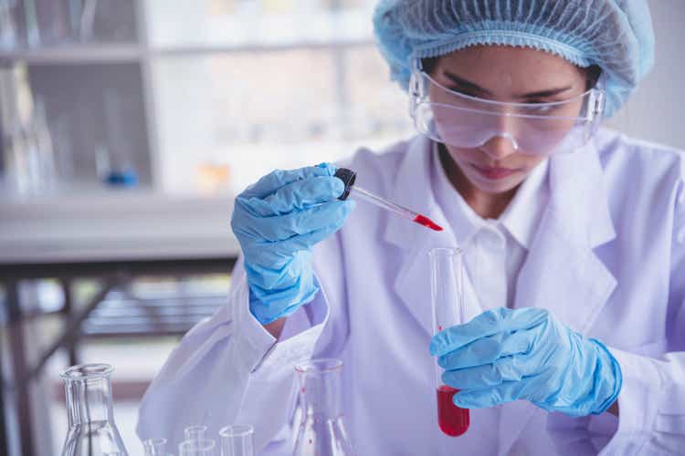 Scientist woman holding chemical test glass tube testing science laboratory. Lab technician holding red drop to glass tube diagnosis blood sample. Asian woman scientist working test medical chemistry