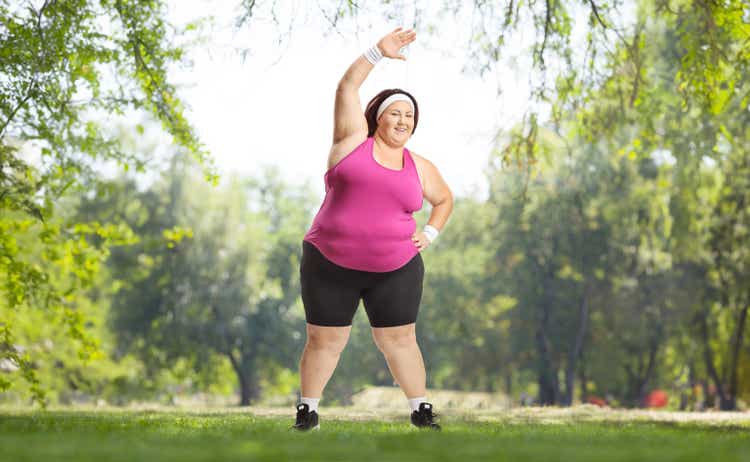 Corpulent woman stretching arms and exercising