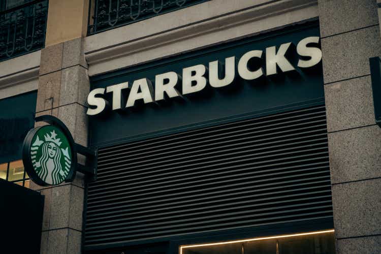 Starbucks Cafe in the old vintage building on the busy street downtown of Madrid. Starbucks logo on the facade of an old building