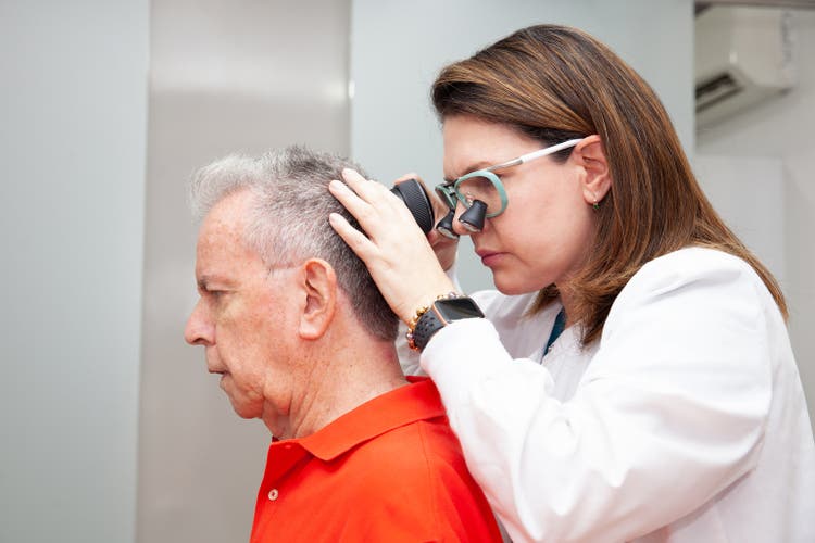 Dermatologist performing a trichoscopy to a senior male patient.
