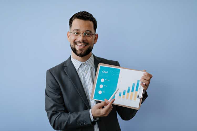 Man with glasses showing chart on clipboard, smiling