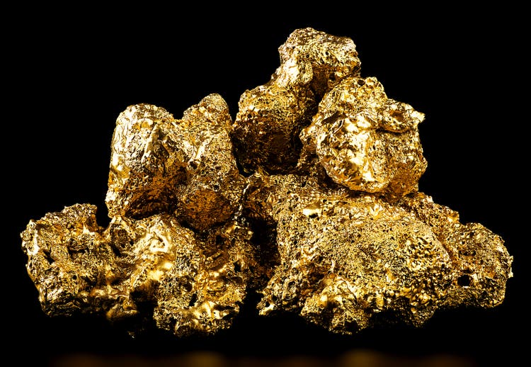 Pile of gold nuggets isolated on a black background. Gold ore.