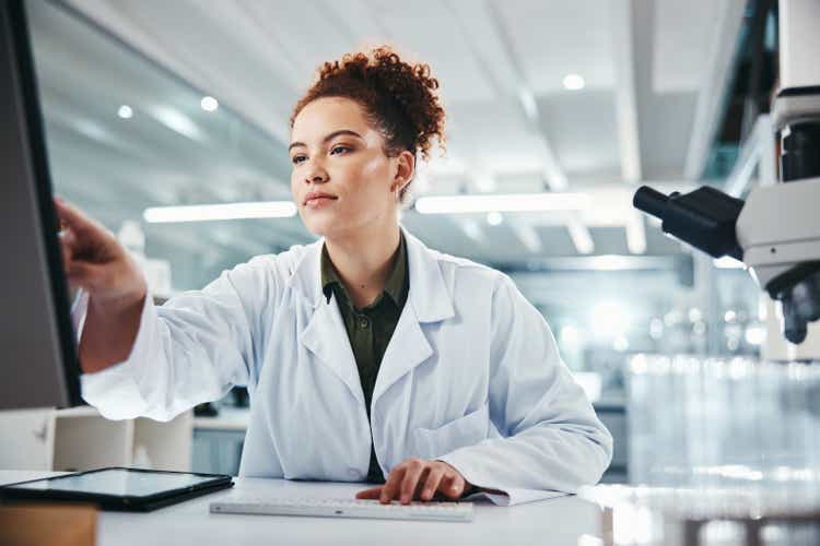 Computer, pointing and science with woman in laboratory for development, innovation or research. Pharmaceuticals, report or review and scientist at work on medical breakthrough, discovery or feedback