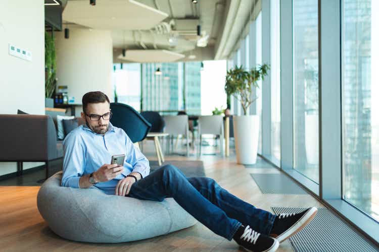 Relaxed businessman working sitting in bean bag with smartphone