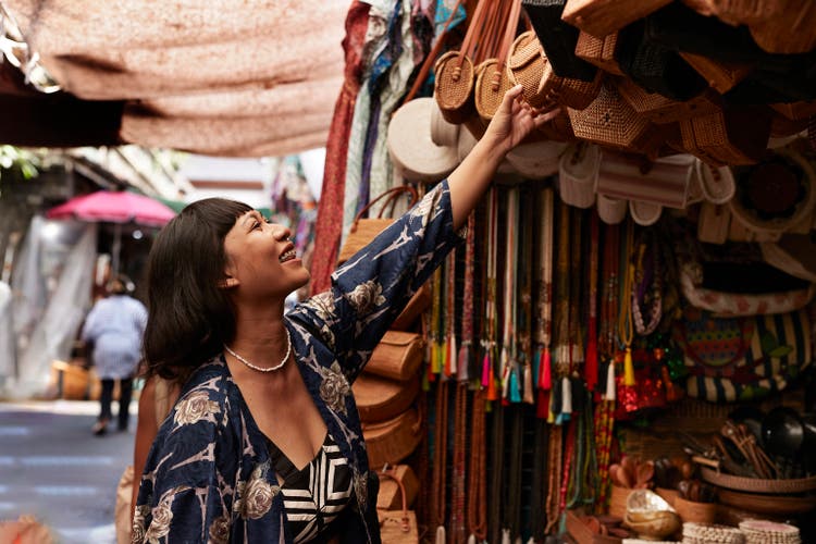Happy female tourist reaching at bags while doing street shopping on vacation