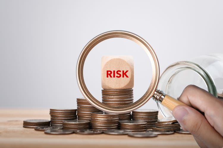 Risk management of finance and investment. magnifier glass focus Risk word on wooden block cube and Heap of coins money for financial banking risk analysis and management, Investment Safety concept.