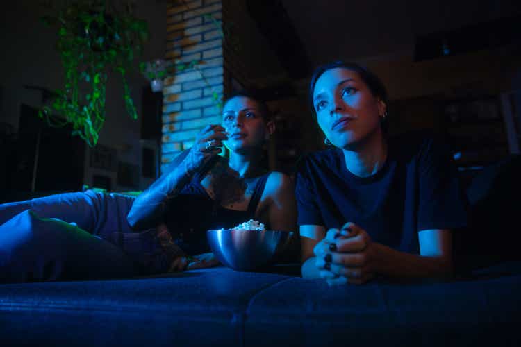 Two young woman looking film and eating popcorn