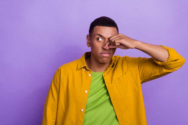 Photo portrait of attractive young male close nose avoid odor empty space dressed stylish yellow outfit isolated on violet color background