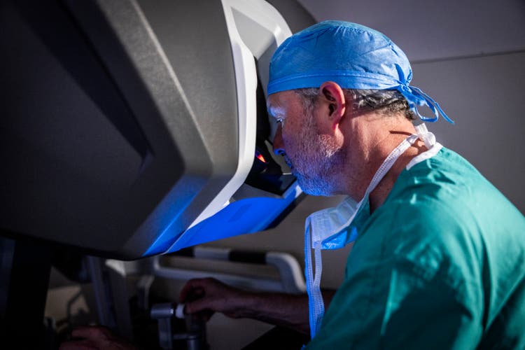 Male surgeon sitting at surgical robotic console