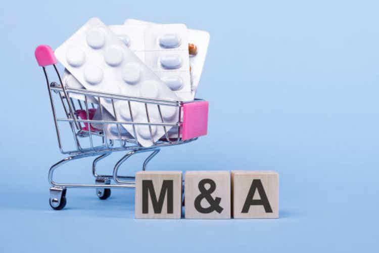 M and A text on a wooden block next trolley with pills. Medical concept