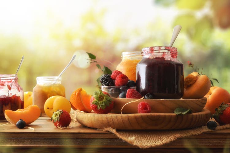 Several jars of jam with different fruits in nature