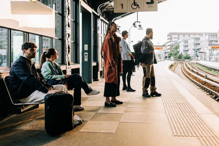 Commuters sitting and standing at platform while waiting for train