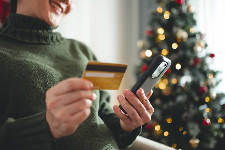 Close-up shot of pregnant woman using smartphone and credit card to buy gifts for Christmas.