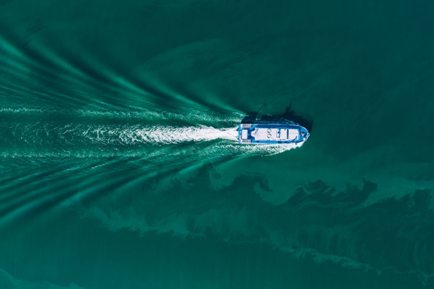 Aerial drone view of shipping offshore vessel or barge in turquoise blue water river sea ocean. Amazing summer landscape