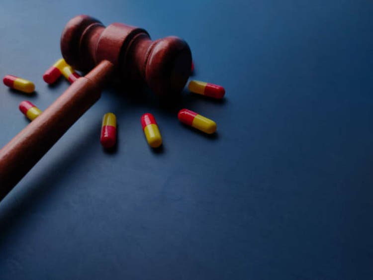 Closeup wooden gavel and medical pill on a blue background with copy space