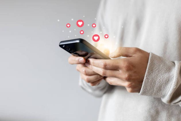 close up young woman hand hold and using smartphone to surf on social media platform and give a heart and love symbol to trendy or popular image or satisfy content for people and lifestyle concept
