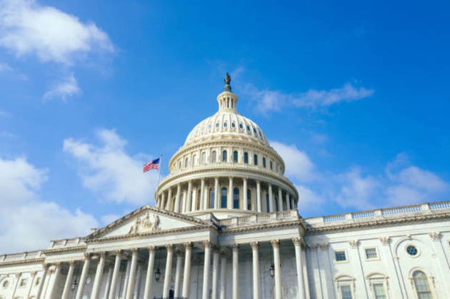 United States Capitol building with American flag over blue sky background, Washington DC