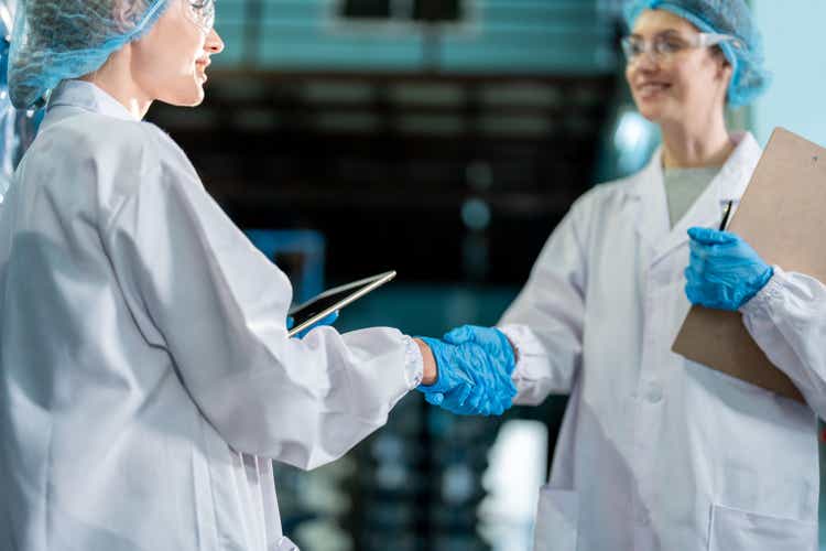 Close up of female scientist work in laboratory at factory warehouse. Attractive woman chemist analysis of a chemical sample in the scientific research laboratory processing bottles of mineral water.