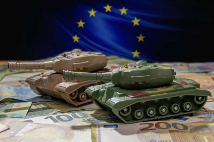 Close-up of toy tanks against the background of unfolded euro notes and the European flag
