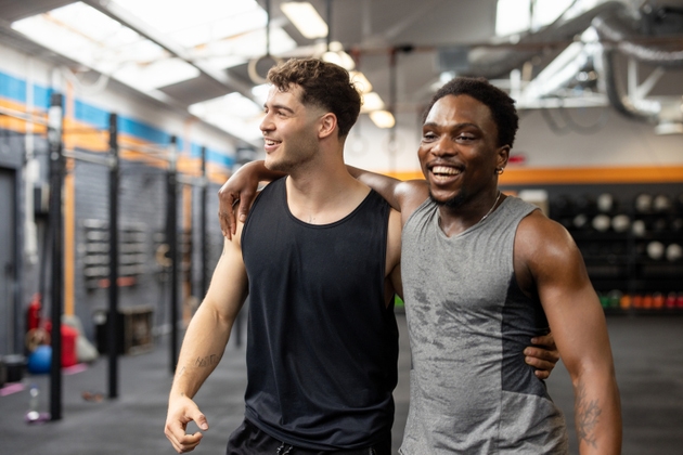 Two men standing together at gym and smiling