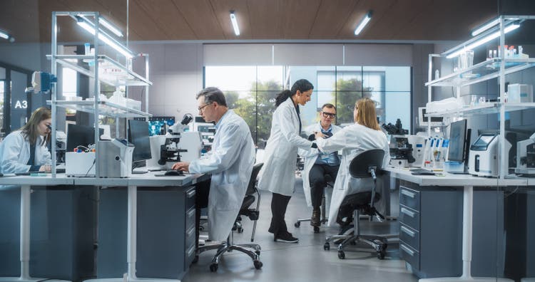 Three Scientists Discussing Latest Bioengineering Discoveries and Sharing Research Data on Vaccine Efficacy. Diverse Male and Female Colleagues Working in a Modern Medical Research Center
