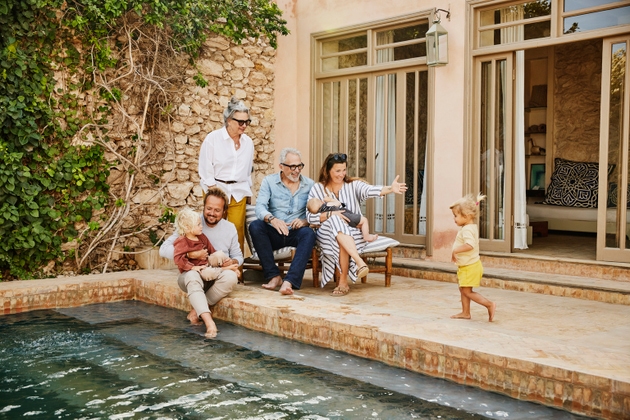 Wide shot smiling multigenerational family relaxing at tropical villa