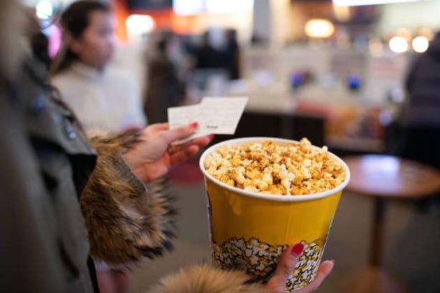 Woman holding popcorn and movie ticket