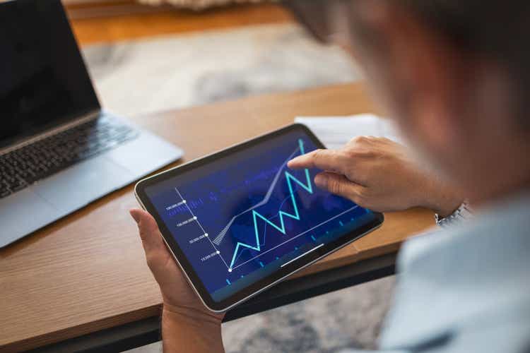 Mature man analyzing financial data on tablet at home