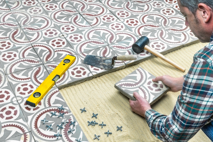 Construction worker installing hydraulic cement tiles.