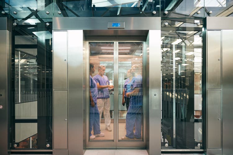 Male and female healthcare professionals inside elevator at hospital