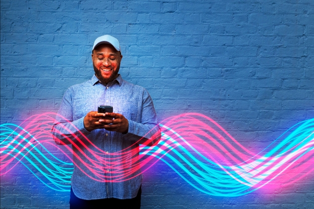 Man interacting with smart phone with curved light trails in front of blue wall
